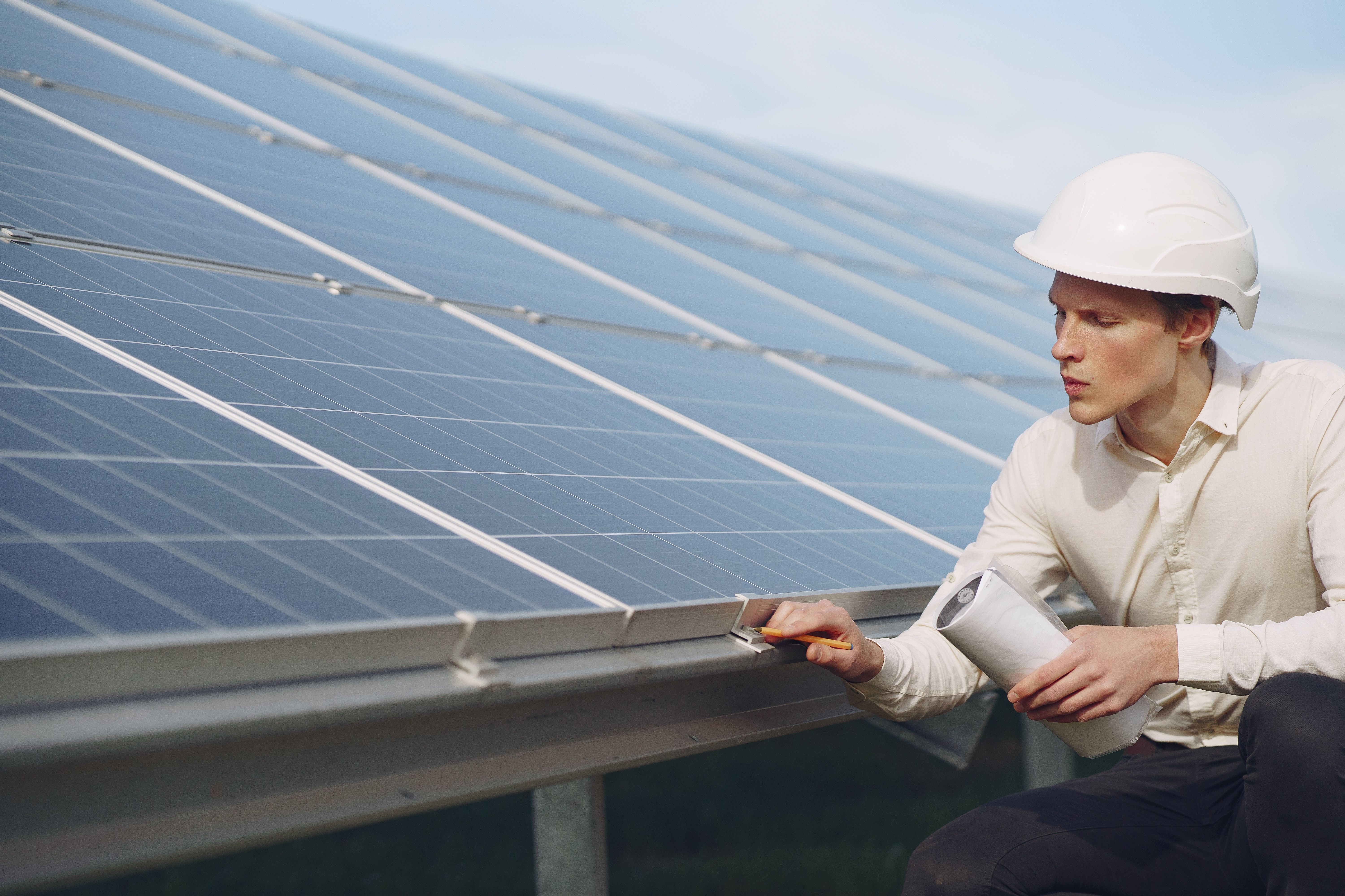 Techniker prüft Solaranlage mit Bauplan auf dem Dach